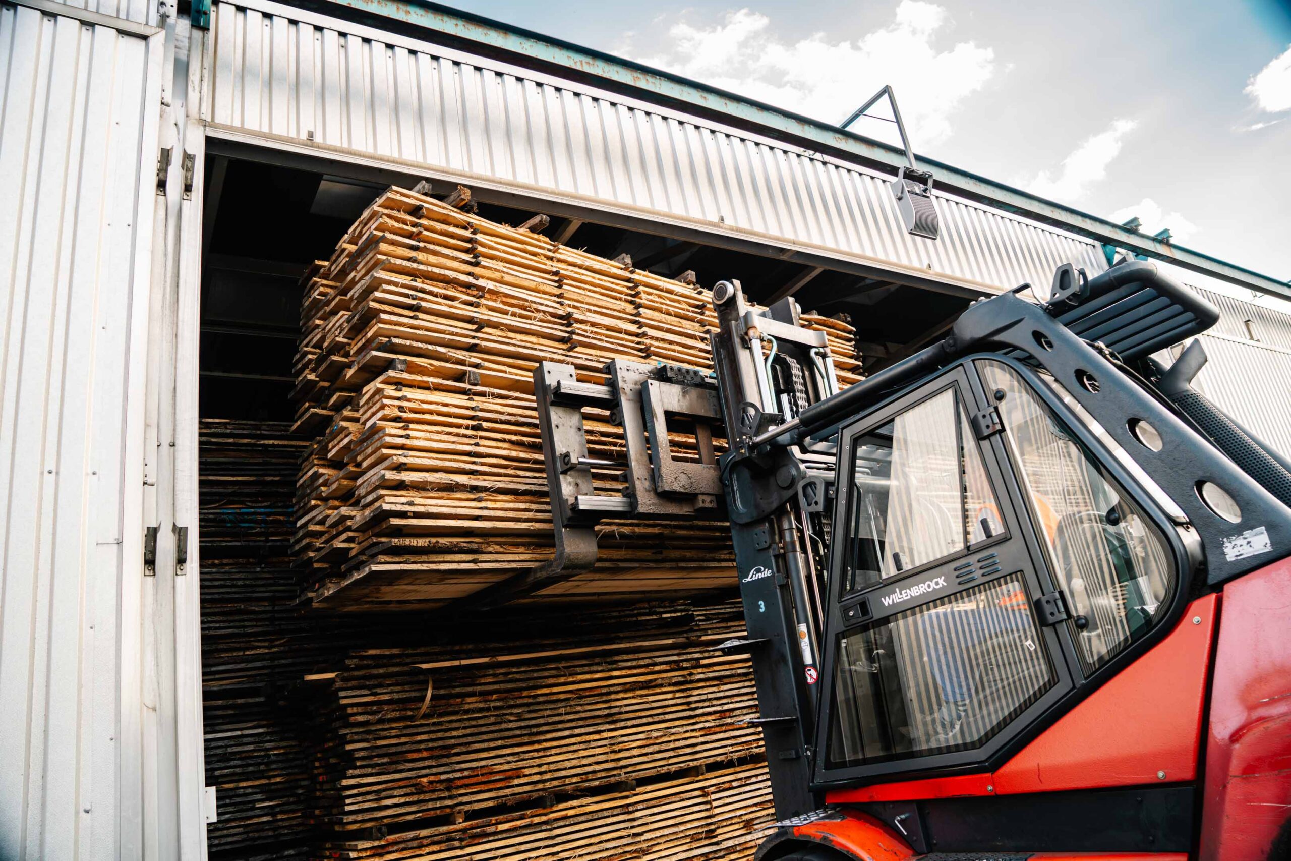Ein Gabelstapler lädt getrocknetes Holz aus einer Halle aus